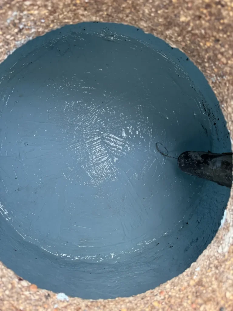 Inside of a round grease trap after repair, covered in a smooth blue-gray lining