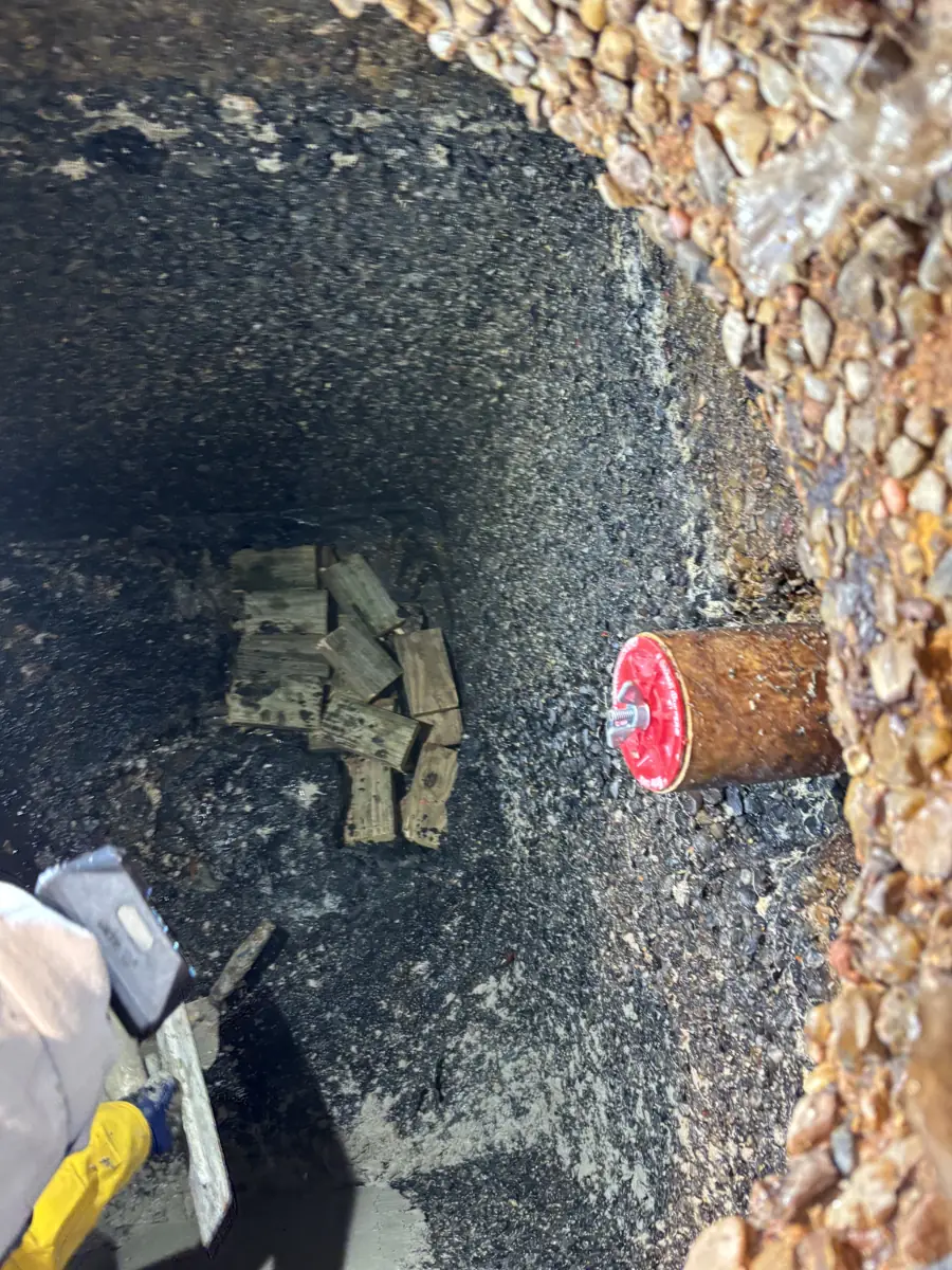 Technician working inside an emptied concrete grease trap, the pipe plugged and the walls cleaned back